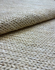 Ziegler & Co. Modern Rug features a thick, braided texture in neutral tones, shown here rolled partially to display details.