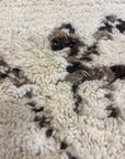 Close-up of Santa Barbara Chic Moroccan rug with a textured, cream-colored background and brown abstract patterns.