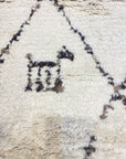 Close-up of Santa Barbara Chic Moroccan rug, featuring a minimalist black and white geometric design on a cream background.