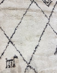 Santa Barbara Chic Moroccan rug with a beige background, black diamond-shaped patterns, and a small geometric figure in one corner.